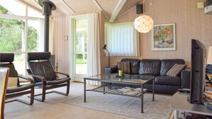 A modern living room with a glass coffee table, leather sofa, and a fireplace. - Stunning home in Gilleleje with kitchen (Gilleleje)