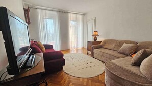 A living room with a sofa, a red armchair, a television, and a lamp.