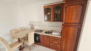 A compact kitchen with a dining table, chairs, and wooden cabinets.