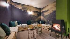 A cozy living room with a sofa, a small table with fruit, and a wood-burning stove. - Basic double rooms (16m²) - Hotel & Restaurant Alpenrose Bayrischzell (Bayrischzell)