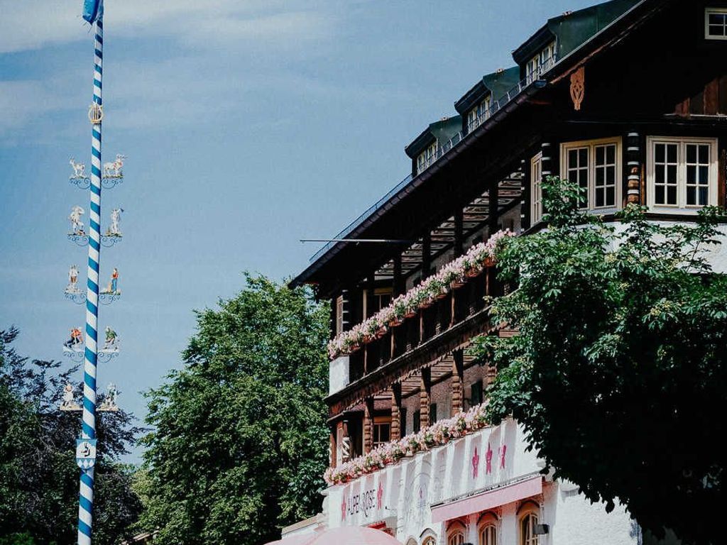 A traditional building with multiple balconies, a sign with text, and a blue-striped pole with figures.