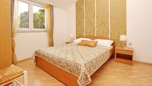 Una camera da letto con un letto in legno, due comodini, una sedia e una finestra con tende.