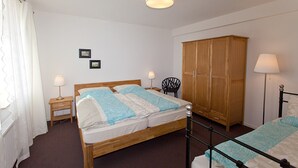 Ein Schlafzimmer mit einem Bett, zwei Nachttischen mit Lampen, einem Kleiderschrank und zwei gerahmten Bildern an der Wand.