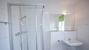 Ein Badezimmer mit Duschkabine, Waschbecken und Spiegel.