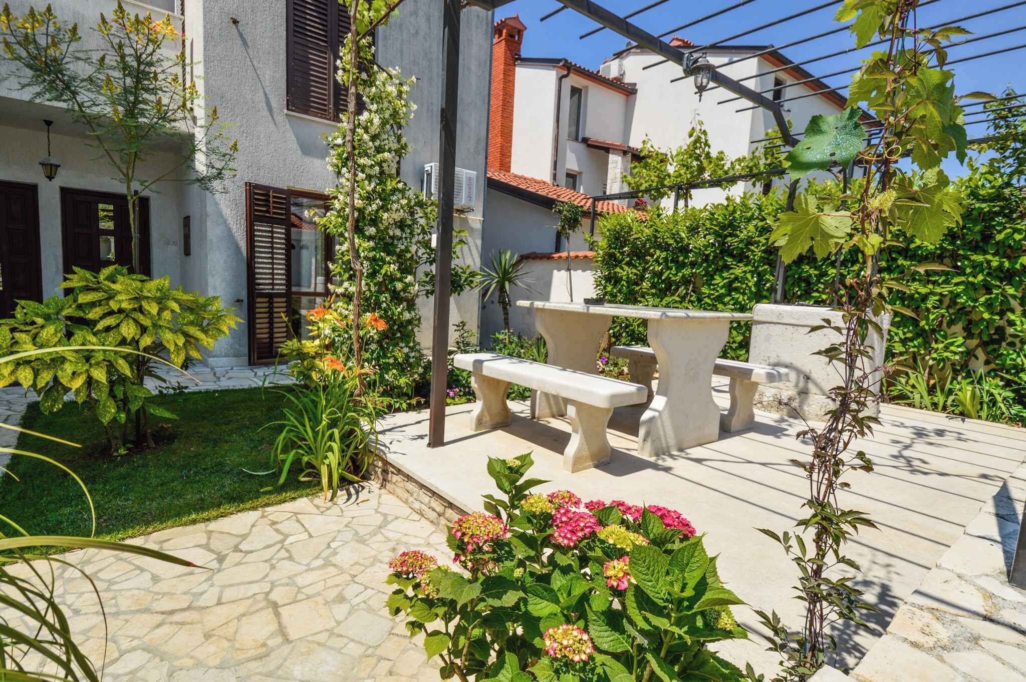 A courtyard with a stone bench, potted plants, and a pergola.