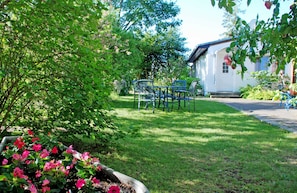 A garden with a table and chairs, a white building, and a pathway.