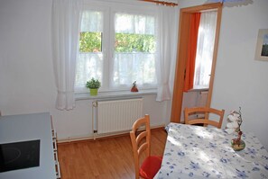 Una habitación con una mesa de comedor, sillas, un radiador y una ventana con cortinas.