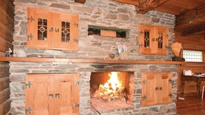 A stone fireplace with wooden cabinets and a lit fire.