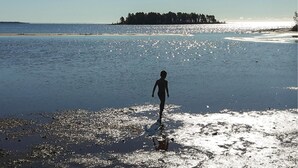 A beach scene with a person walking on the shore.