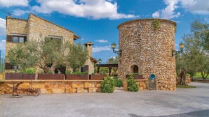 A stone building with a cylindrical tower, a covered patio, and a paved courtyard. - Lovely home in Muro with private swimming pool, can be inside or outside (Muro)