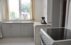 A kitchen with a sink, cabinets, a stove, and a coffee maker.