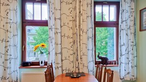 A dining area with a round table, chairs, a vase with flowers, and a statue on the windowsill. - Labedz (LA16) - LA16 (Swinoujscie)
