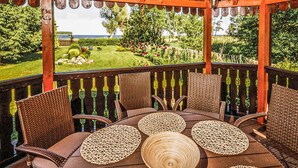 Um pátio ao ar livre com móveis de vime e vista para um jardim e o oceano.