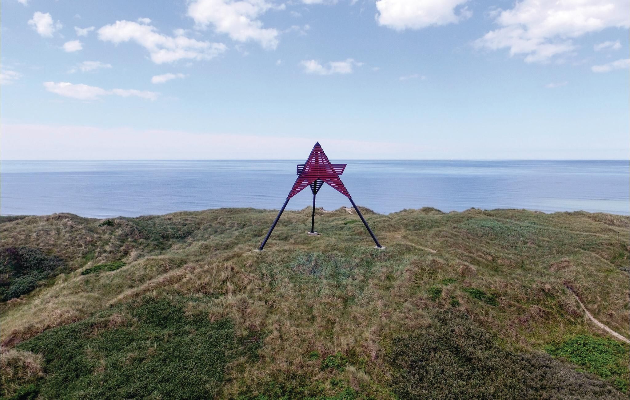 Eine sternförmige Skulptur auf einer grasbewachsenen Anhöhe mit Blick auf das Meer.