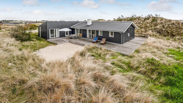 A modern beach house with a large deck, outdoor seating, and a view of the surrounding dunes. - Lovely home in Hvide Sande with WiFi (Hvide Sande)