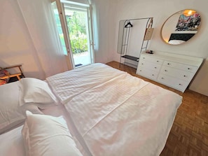 A bedroom with a bed, a dresser, a mirror, and a view of the outdoors. - Holiday apartment directly by the sea (Novi Vinodolski)