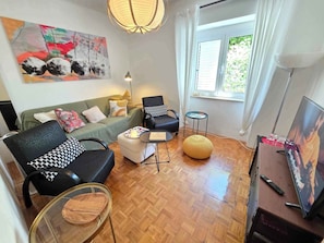 A living room with a sofa, two armchairs, a coffee table, a small side table, a lamp, a TV, and a painting on the wall. - Holiday apartment directly by the sea (Novi Vinodolski)