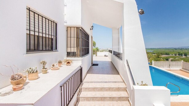 Um edifício moderno com piscina, escadaria e plantas em vasos na varanda.