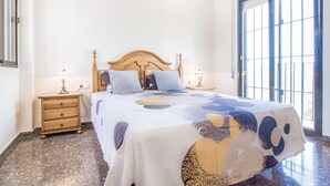 Quarto com cama de madeira, duas mesinhas de cabeceira e uma janela grande.