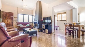 Uma sala de estar ampla com um sofá de couro, uma mesa de centro, uma lareira e uma televisão.