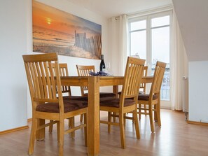 Un coin repas avec une table et des chaises en bois, un tableau accroché au mur et une vue par la fenêtre.