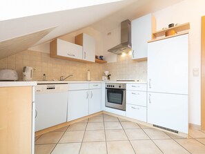 Une cuisine avec des meubles blancs, une cuisinière et un lave-vaisselle.