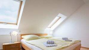 Ein Schlafzimmer mit Oberlicht, einem Holzbettgestell, Nachttischen und einem Nachtschränkchen.