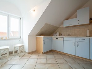 Une cuisine avec des meubles de couleur bleu clair, un plan de travail blanc et une fenêtre donnant sur des immeubles.