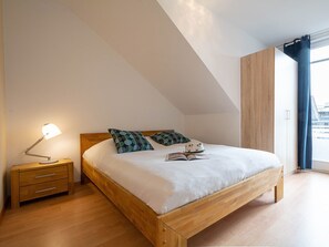 Une chambre à coucher avec un lit en bois, une table de chevet avec une lampe et une fenêtre avec des rideaux.