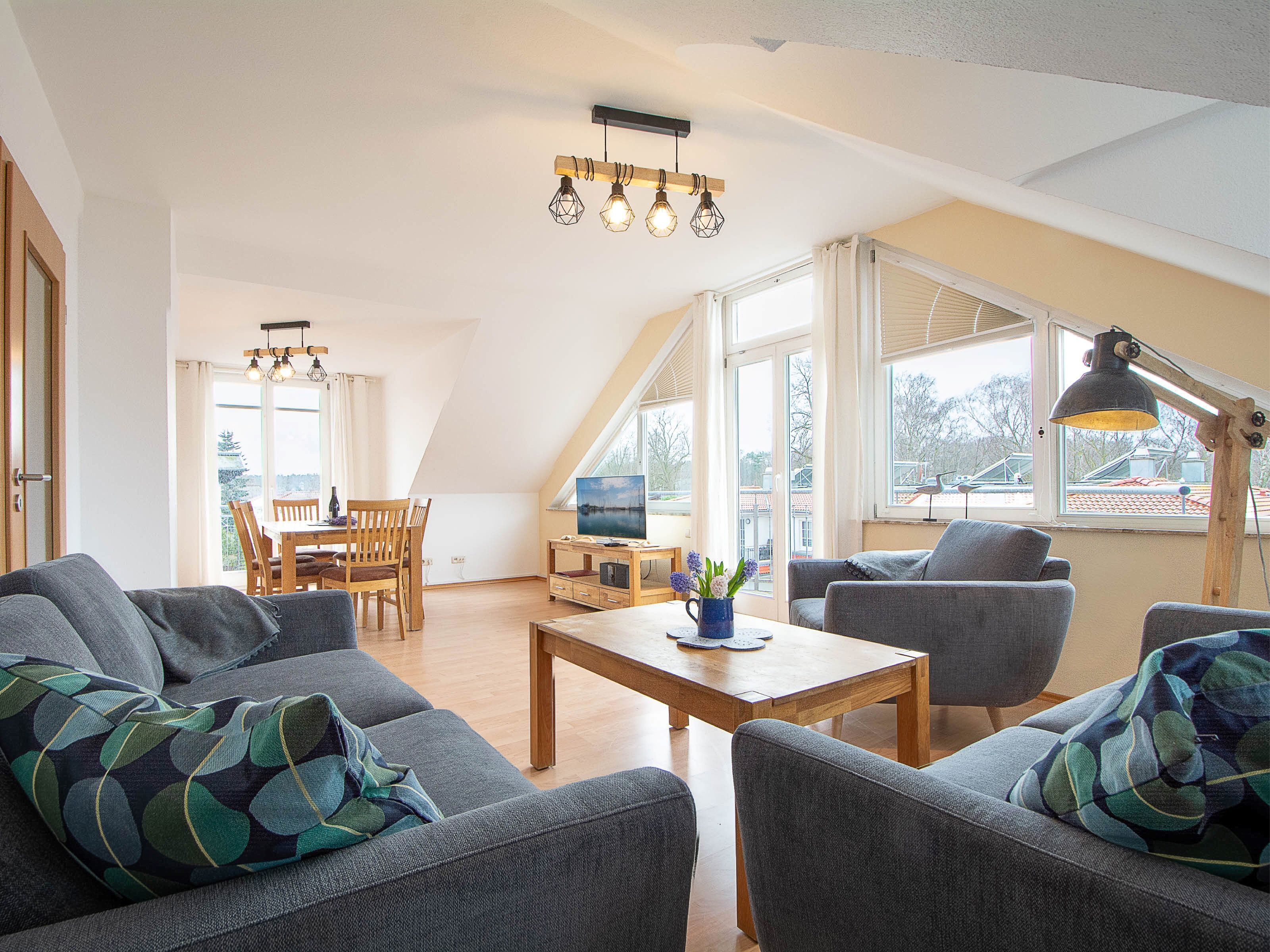 Een ruime woonkamer met hoge plafonds, een eettafel en comfortabele zitplaatsen.