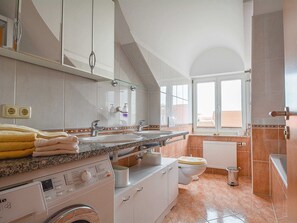 Un bany modern amb un mirall gran, dues rentadores, un vàter i una màquina de rentar.