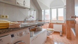 Un baño moderno con un espejo grande, lavamanos dobles, inodoro y lavadora.