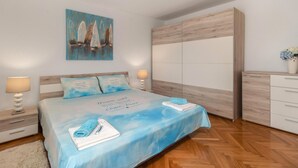 A bedroom with a bed, nightstands, a wardrobe, and a painting on the wall. - Cozy apartment in Dobrinj with WiFi (Dobrinj)