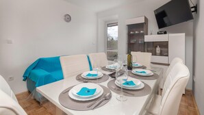 A dining area with a white table set for four, including plates, cutlery, and wine glasses. - Cozy apartment in Dobrinj with WiFi (Dobrinj)