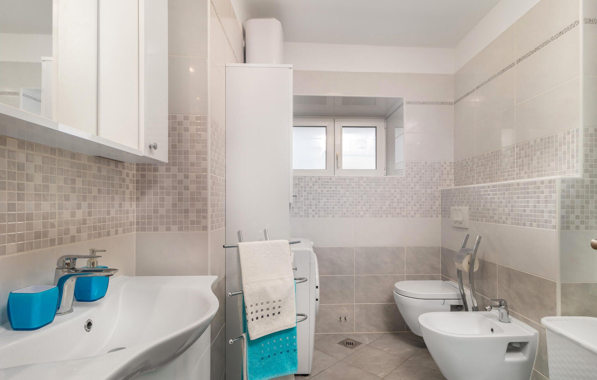 A modern bathroom with a white sink, a bidet, and a toilet.