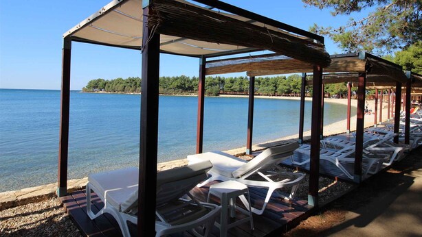 A beachside pavilion with lounge chairs and a view of the sea. - Holiday apartment with terrace (Novigrad)