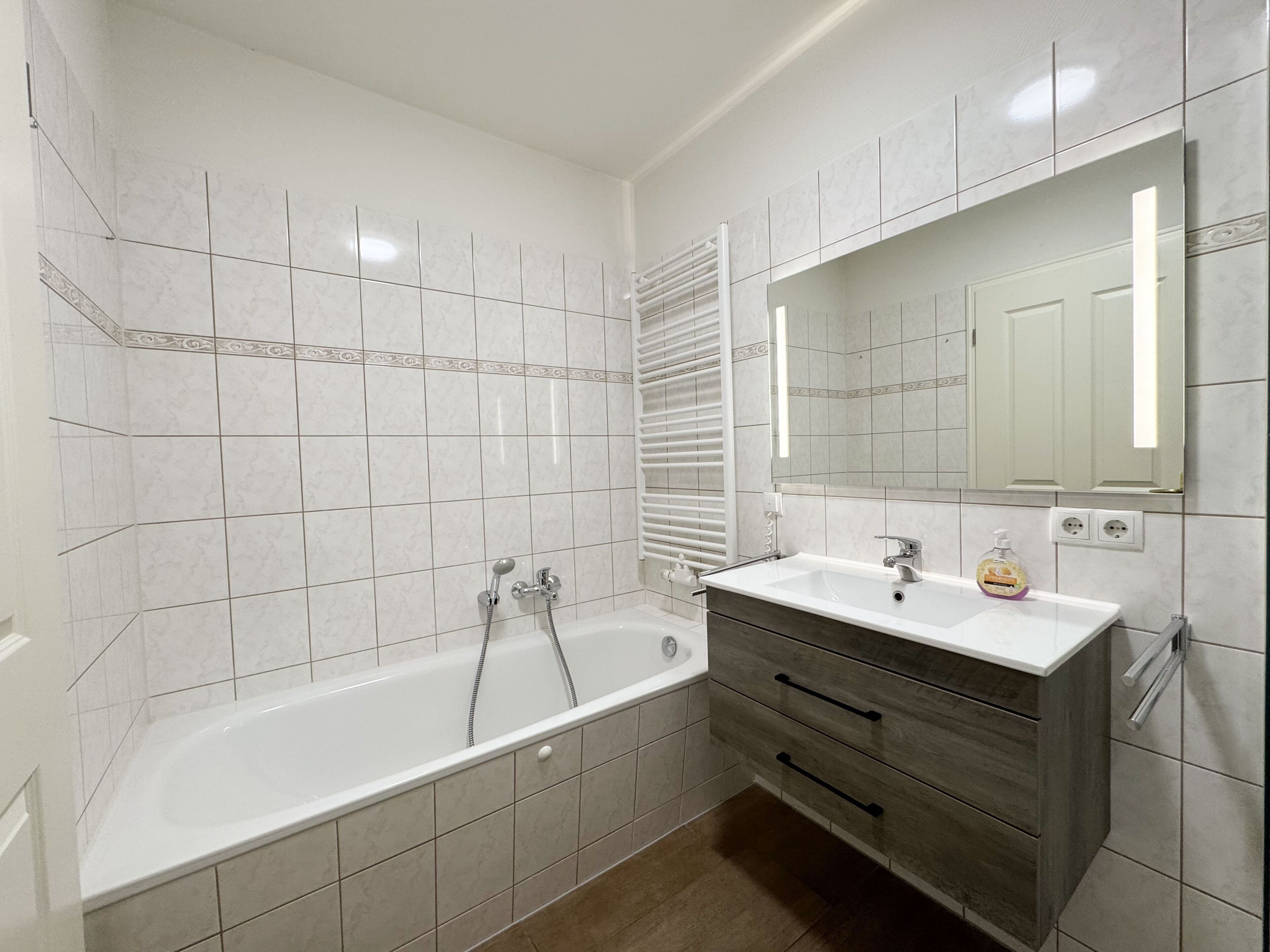 A modern bathroom with a bathtub, vanity, and a mirror.