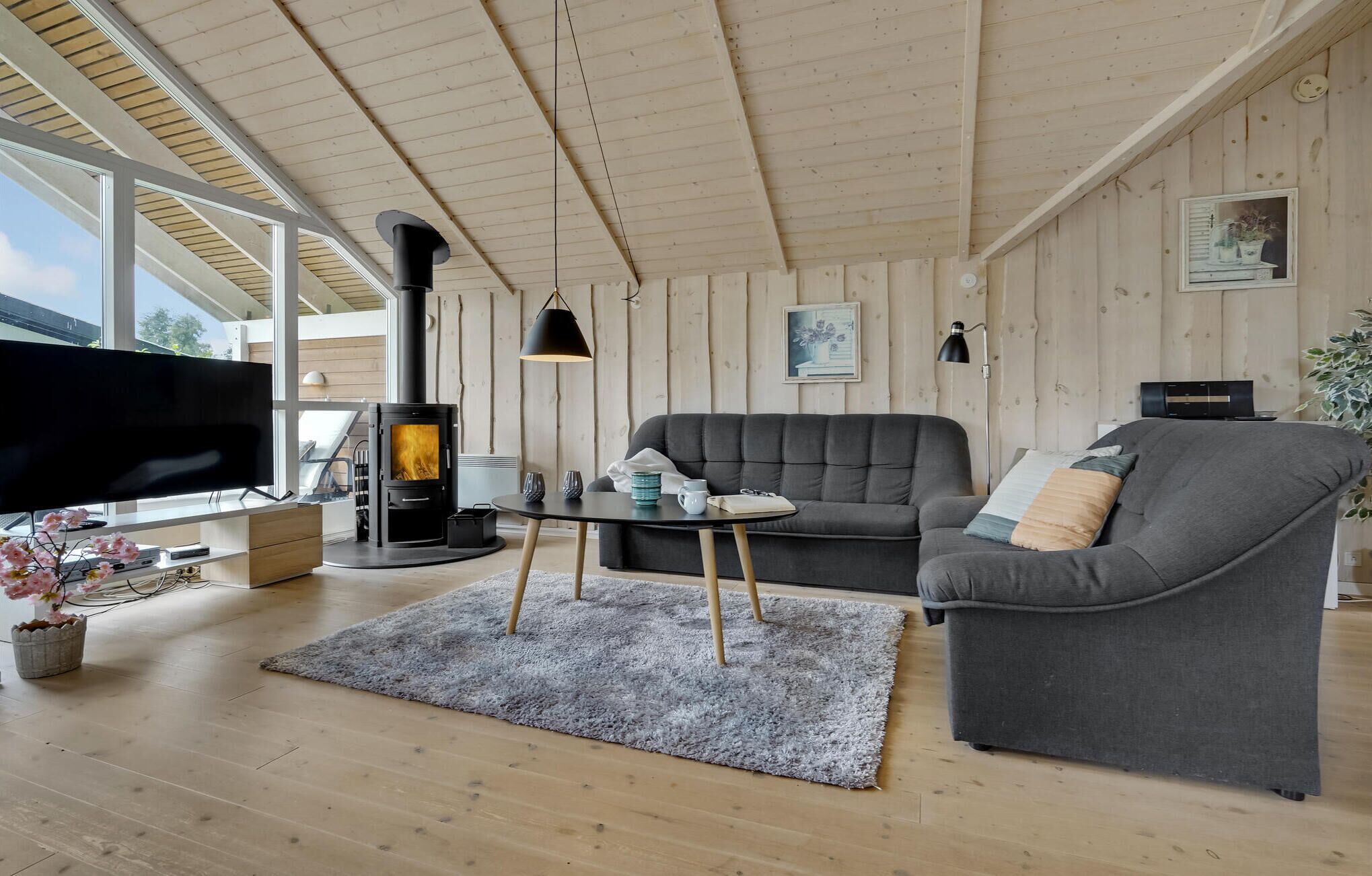Een moderne woonkamer met een open haard, een bank, een televisie en een eettafel.
