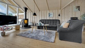 Een moderne woonkamer met een open haard, een bank, een televisie en een eettafel.