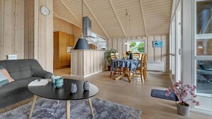 Een ruime woonkamer met een eettafel, een bank en een keuken op de achtergrond.