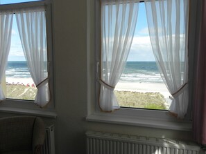 Ein Zimmer mit zwei Fenstern mit Blick auf einen Strand.