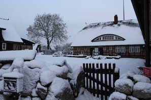 Un edificio cubierto de nieve con un diseño tradicional, que presenta una pared de piedra y una puerta de madera.