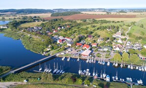 Uma marina com barcos atracados, rodeada por casas e vegetação.