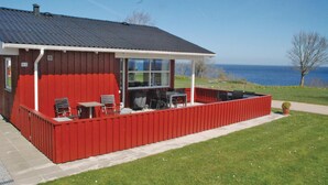 A red cabin with a covered patio, outdoor seating, and a view of the sea. - Amazing home in Sydals with WiFi (Sydals)