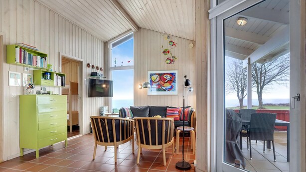 A cozy living room with a large window, a green cabinet, a flat-screen TV, and a colorful abstract painting. - Amazing home in Sydals with WiFi (Sydals)