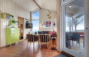 Ein gemütliches Wohnzimmer mit großem Fenster, einem grünen Schrank, einem Flachbildfernseher und einem farbenfrohen abstrakten Gemälde.