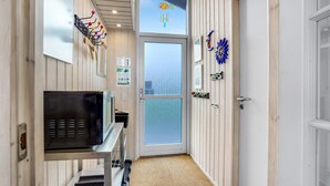 A narrow hallway with a door leading to a balcony, a small kitchen area with a refrigerator, and decorative wall art. - Amazing home in Sydals with WiFi (Sydals)