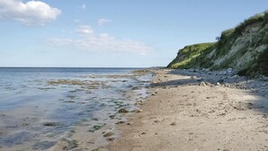 A beach with clear water, rocky shore, and a grassy cliff. - Amazing home in Sydals with WiFi (Sydals)