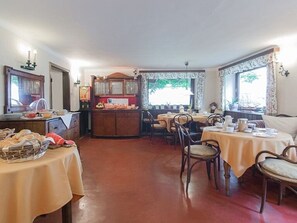 A dining area with tables, chairs, a buffet station, and a view of the outdoors.