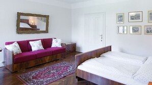 Une chambre à coucher avec un lit en bois, un canapé rouge, un miroir et des tableaux encadrés accrochés au mur.
